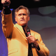 Evil Dead star Bruce Campbell stands onstage addressing fans at a horror convention.